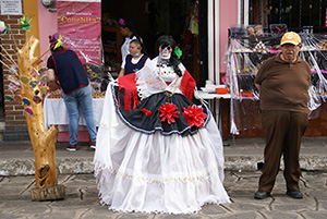 Photo: Catrina in white dress with black apron and read flowers